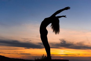 Gün batımında siluet kadın koç yoga uygulaması. Yoga konsepti.