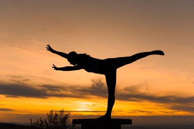Siluet kadın gün batımında yoga antrenmanı yapıyor. Virabhadrasana III. Savaşçı III