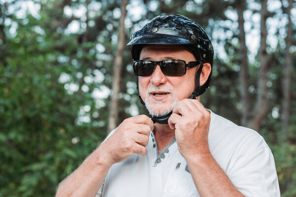 Middle aged man fixing his helmet for a motor bike ride. Transportation concept