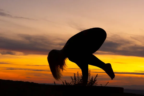 Silhouet vrouw coach yoga praktijk bij zonsondergang. Kraan, kraaienhouding. — Stockfoto