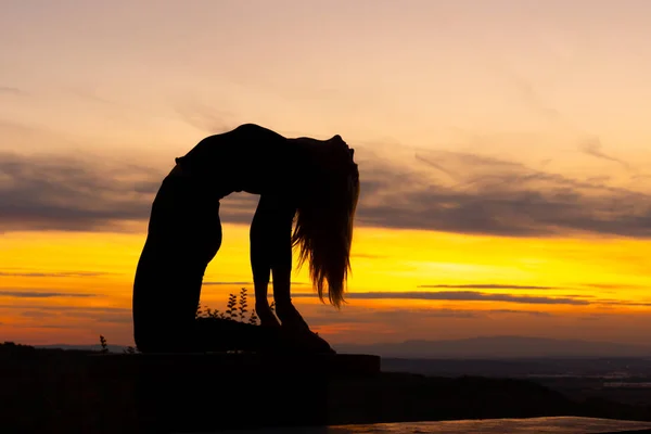 Silhouet vrouw coach yoga praktijk bij zonsondergang. Yoga concept. Kamelenspuit. — Stockfoto