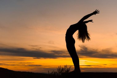 Gün batımında siluet kadın koç yoga uygulaması. Yoga konsepti.