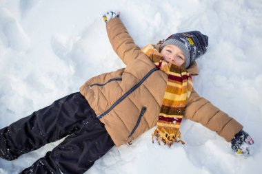 Çocuk eğleniyor, dışarıda oynuyor, karla çevrili, yıldız yapıyor..