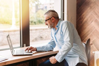 Kafede bilgisayarla çalışan orta yaşlı yakışıklı bir adam. İş konsepti