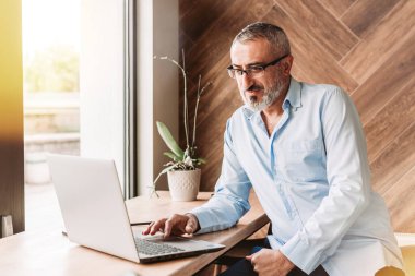 Kafede bilgisayarla çalışan orta yaşlı yakışıklı bir adam. İş, modern konsept