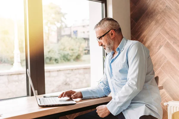 Kafede bilgisayarla çalışan orta yaşlı yakışıklı bir adam. İş, modern konsept