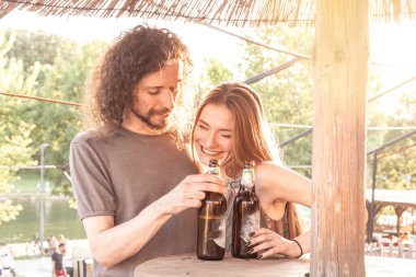 Genç hippi çift, öğleden sonra güneşli bir barda bira içiyor.