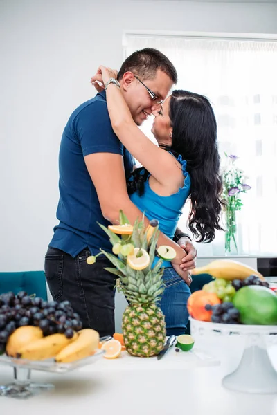 과일로 둘러싸인 부엌에서 행복 한 부부가 키스하는 모습. — 스톡 사진
