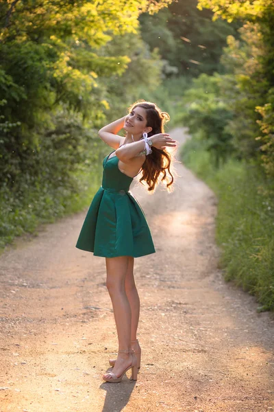 Bella ragazza bruna in abito verde glamour e tacchi alti, scarpe in natura. Pronto per la notte del ballo — Foto Stock