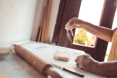 Kadın eli hamura un ekliyor. Kruvasan rulosu yapma süreci