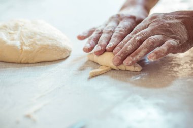 Kadın eli hamuru rulo şeklinde yuvarlıyor. Kruvasan rulosu yapma süreci