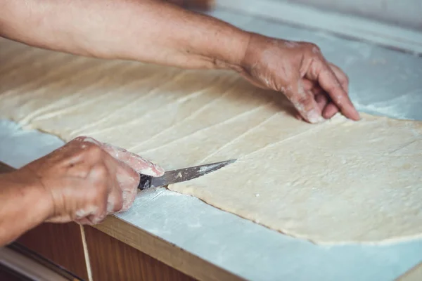 Женские руки режут тесто ножом. Процесс изготовления круассанов — стоковое фото