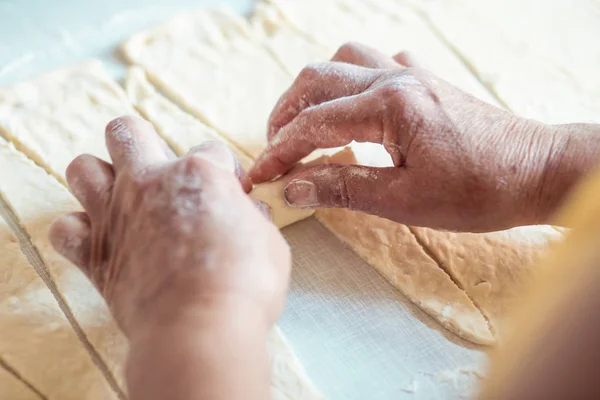 Female hands rolling dough into rolls. Process of making croissant rolls — Stock Photo, Image