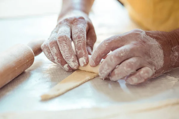 Les mains féminines roulent la pâte en rouleaux. Processus de fabrication de rouleaux croissant — Photo