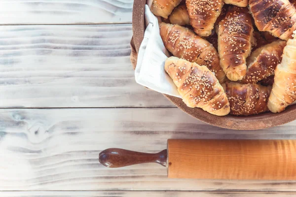 Rotoli di mezzaluna sul tavolo di legno con rullo di pasta. Croissant fatti in casa . — Foto Stock