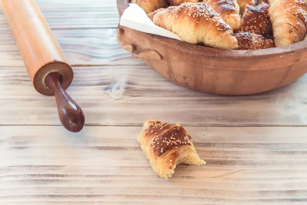 Rotoli di mezzaluna sul tavolo di legno con rullo di pasta. Croissant fatti in casa . — Foto Stock