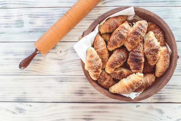 Rotoli di mezzaluna sul tavolo di legno con rullo di pasta. Croissant fatti in casa . — Foto Stock