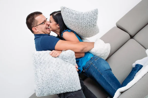 Casal se divertindo na sala de estar. Luta travesseiro — Fotografia de Stock