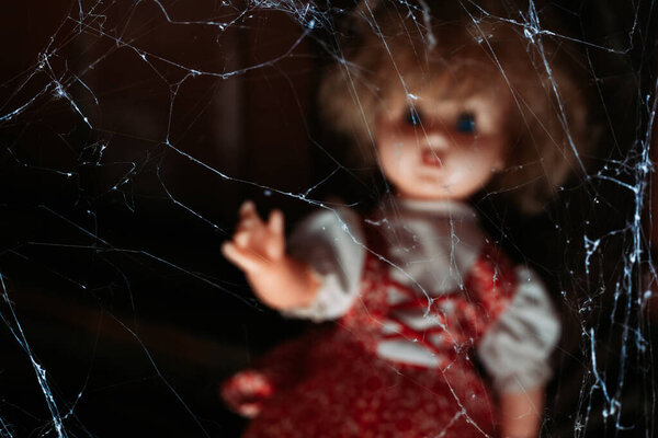 Паутина со старой куклой вне фокуса в фоновом режиме. Концепция Хэллоуина

