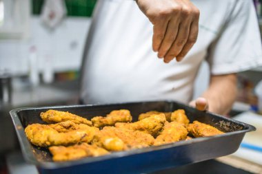 Şef taze kızarmış tavuk külçelerini tuzluyor. Restoran yemeği hazırlığı.