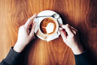 Müşteri eli yakın plan ve taze kapuçino masada. Kahve molası. Üst görünüm