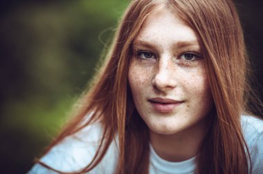 Genç, çilli, gülümseyen kızıl kızın yakın plan portresi.