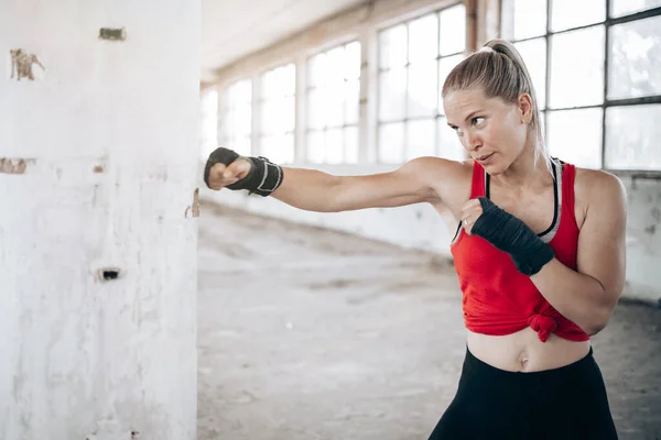 Portrait of young, fit female boxer practice with bandage on her hands.