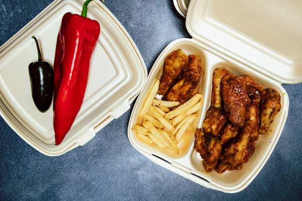 Top view of carton container with grilled chicken nuggets and fries, ready for take-out