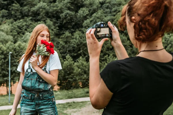 Женщина Фотограф Фотографирует Прекрасную Рыжую Девушку Подростка Букетом Роз Стрельба — стоковое фото