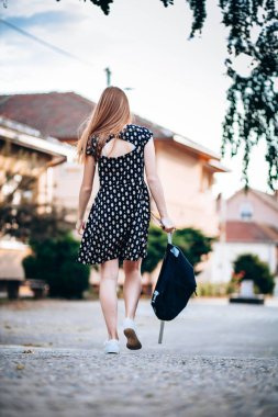 Ergen bir öğrencinin arka planı, okula gitmesi, sırt çantasını elinde taşıması.