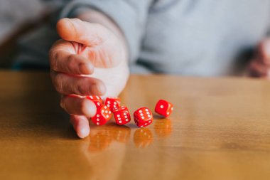 Kadın eli masaya altı kırmızı zarla vuruyor. Yamb, zar oyunu