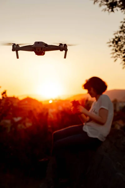 Young woman flying drone in the park. Sunset light