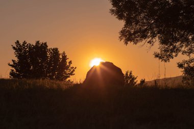 Parktaki kayanın arkasında güneş batıyor. Yaz dönemi arkaplanı