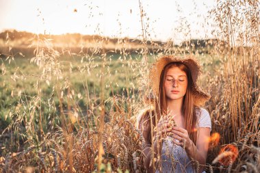 Buğday tarlasında çilli, genç, kızıl saçlı, yaz şapkası takan bir kızın portresi. Boşluğu kopyala