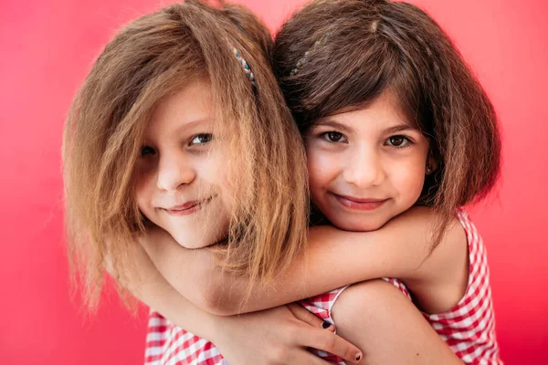 2人の女の子 姉妹しっかりと抱擁 幸せそうに見える ピンクの背景に隔離された — ストック写真