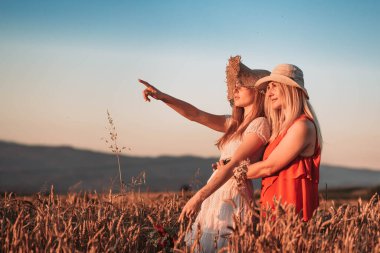 Anne ve kızı sarılıp bir şeye bakıyor. Kız bir şeyi işaret ediyor.