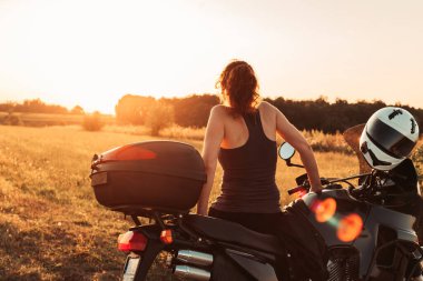 Bisikletinin üzerinde oturan bayan motorcu, dinleniyor. Öğleden sonra ışığı, boşluğu kopyala