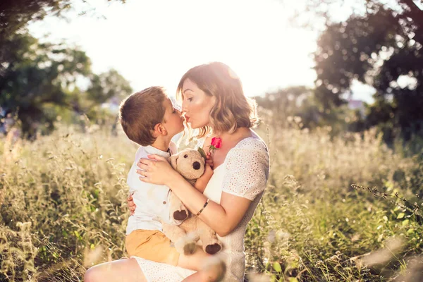 美しい 若いお母さんは唇に彼女の息子にキス 母親のためにバラを持っている少年 自然写真 母の日 — ストック写真