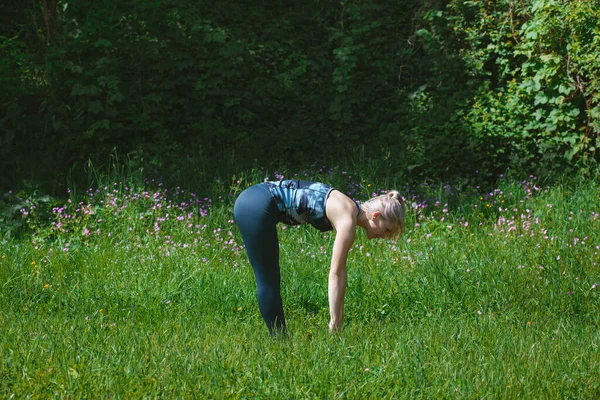 Blonde girl doing upward forward fold pose. Urdhva Uttanasana. Yoga concept