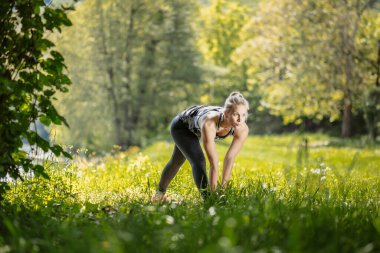 Sarışın kız doğada piramit pozu veriyor. Parsvottonasana. Yoga konsepti