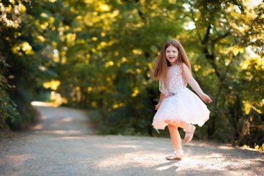 Beyaz elbiseli küçük kızıl çok mutlu görünüyor.