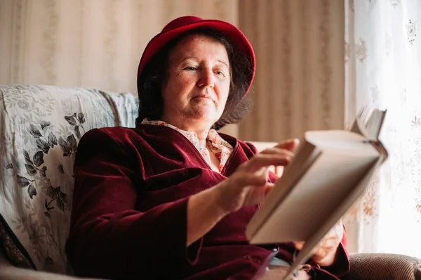 Elderly Woman Hat Reading Book Window Turning Page — Stock Photo, Image