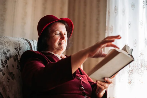 Uma Idosa Com Chapéu Ler Livro Janela Virando Página — Fotografia de Stock