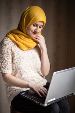 Modern Müslüman dizüstü bilgisayarda çalışıyor, gülümsüyor.