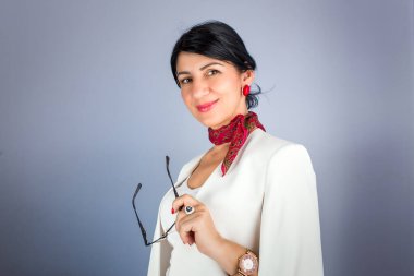 Gözlük tutan ve gülümseyen zarif esmer kadının portresi. Mavi arkaplanda izole