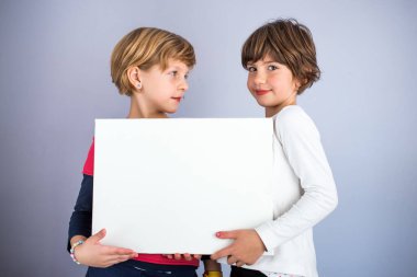 İki küçük kızın elinde boş beyaz tahta var. Boşluğu kopyala, yazmak için boşluk
