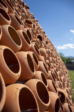 Mavi gökyüzüne karşı dekoratif bir duvara katlanmış kil kaplar.