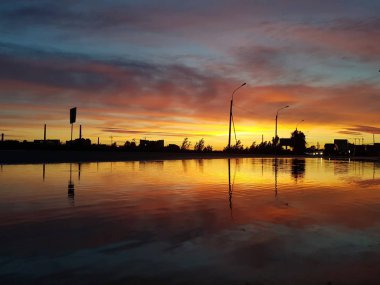 Gün batımının güzel manzarası. Gökyüzünde ve suyun yansımasında sarı, kırmızı ve pembe