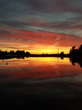 Gün batımının güzel manzarası. Gökyüzünde ve suyun yansımasında sarı, kırmızı ve pembe
