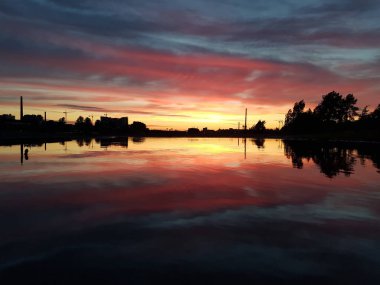 Gün batımının güzel manzarası. Gökyüzünde ve suyun yansımasında sarı, kırmızı ve pembe